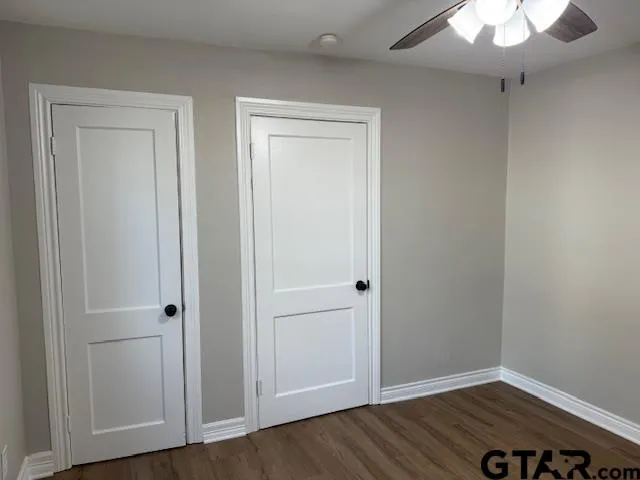 an empty room with wooden floor ceiling fan and windows
