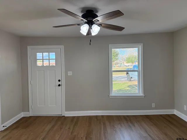 a view of an empty room with wooden floor and a window