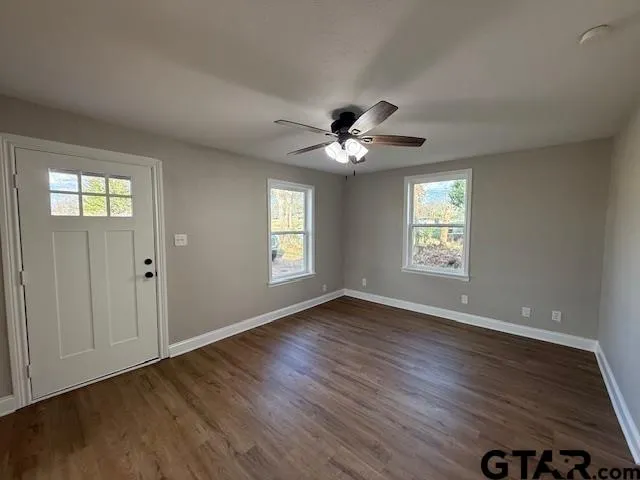 a view of an empty room with a window and wooden floor