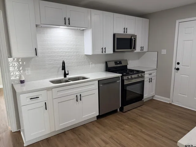 a kitchen with cabinets stainless steel appliances and wooden floor