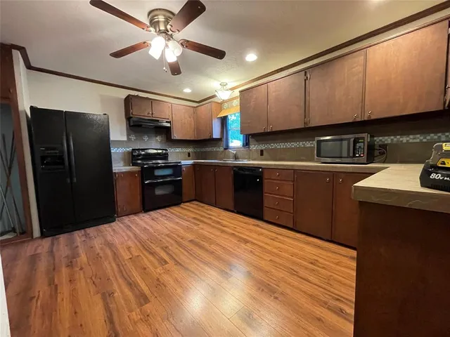 a kitchen with stainless steel appliances granite countertop a refrigerator a sink dishwasher a stove top oven a refrigerator and cabinets