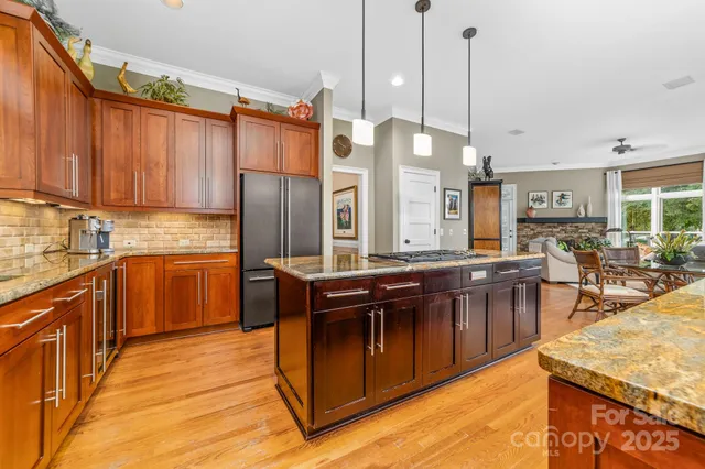 a kitchen with stainless steel appliances granite countertop a stove a sink dishwasher a refrigerator and a wooden cabinets