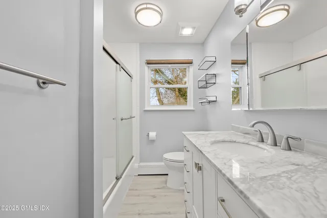 a bathroom with a granite countertop sink a toilet a shower and a mirror