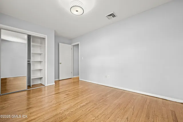an empty room with wooden floor and closet