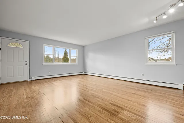 an empty room with wooden floor and windows