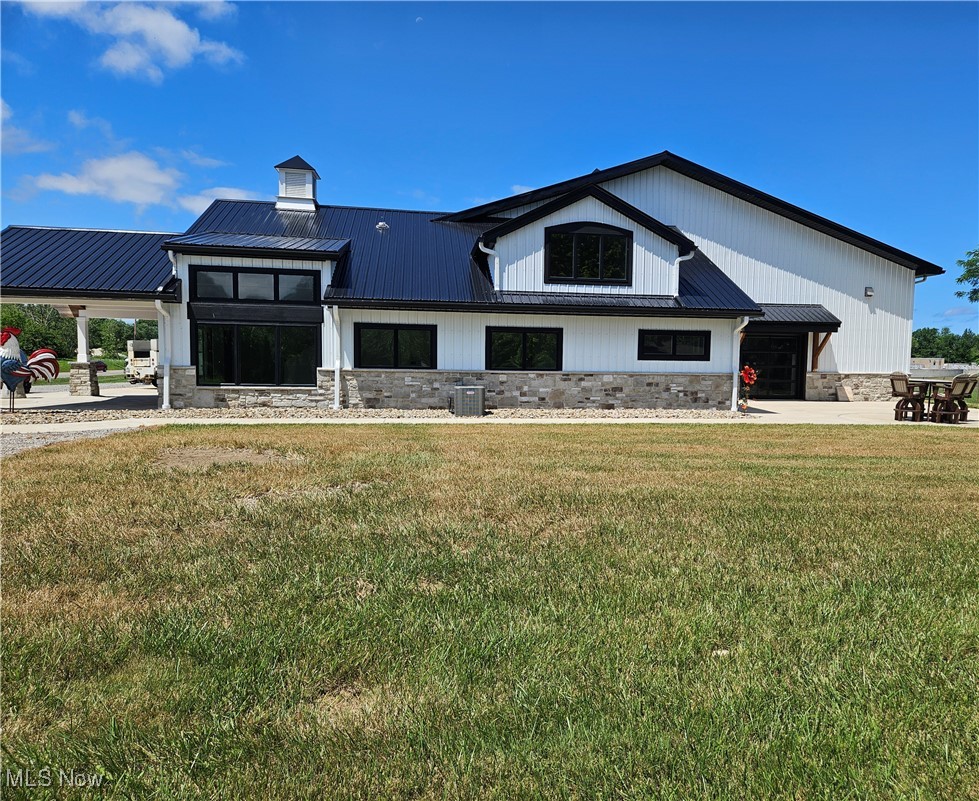 1180 North County Line Road Geneva, OH 44041 - Photo 2 of 33 View of front facade featuring stone siding, a metal roof, and a front lawn