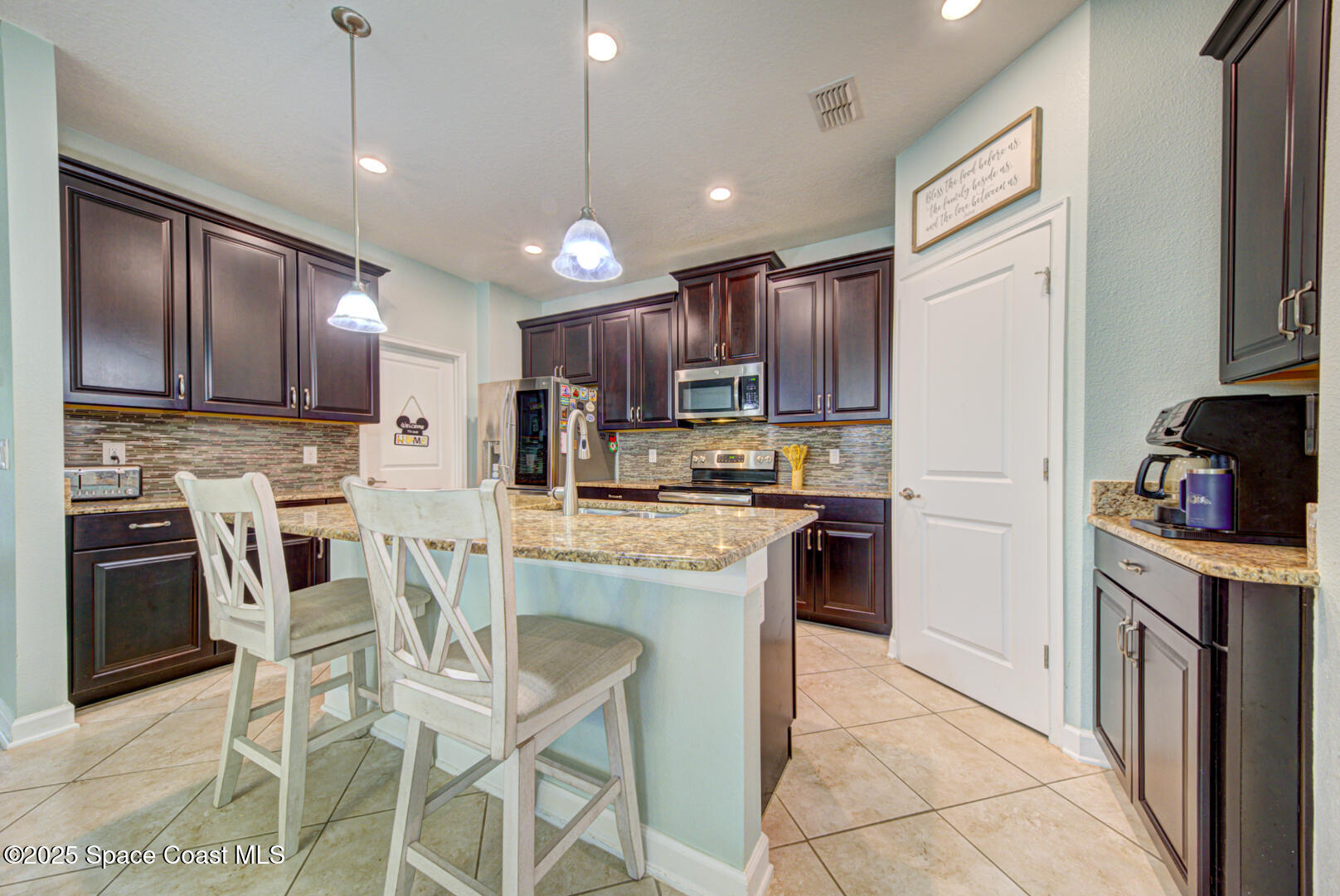 3142 Dark Sky Drive Harmony, FL 34773 - Photo 23 of 54 a kitchen with stainless steel appliances granite countertop a stove top oven a refrigerator a sink with a dining table and chairs