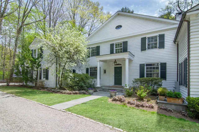 a front view of a house with a garden and trees