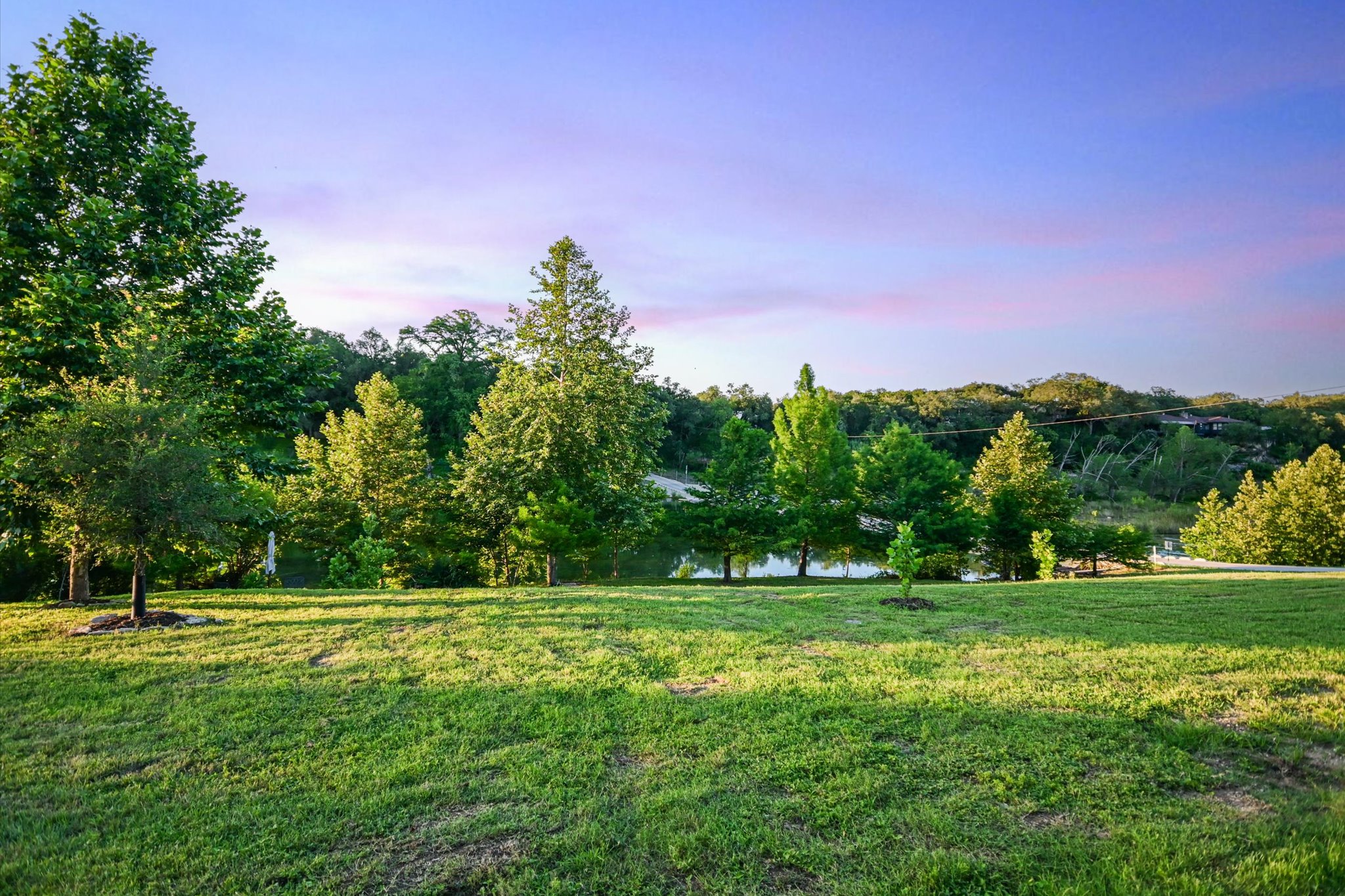 2411 Spoke Hollow Road Wimberley, TX 78676 - Photo 25 of 37 Green grounds extend to a waterfront setting, offering natural beauty and peaceful views.