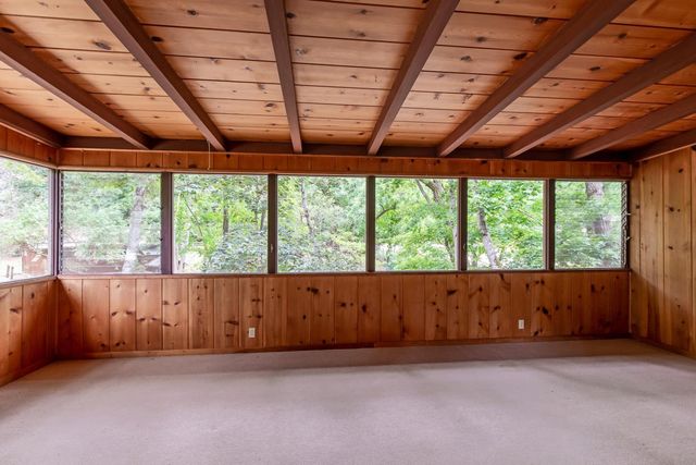 an empty room with large windows and wooden roof