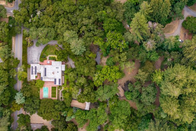 an aerial view of residential house with outdoor space and trees all around