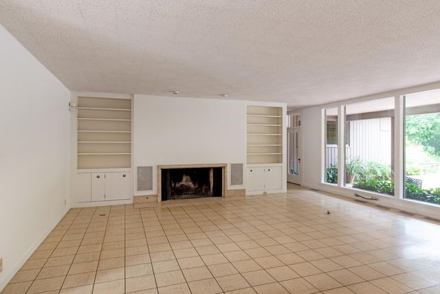 an empty room with windows and fireplace