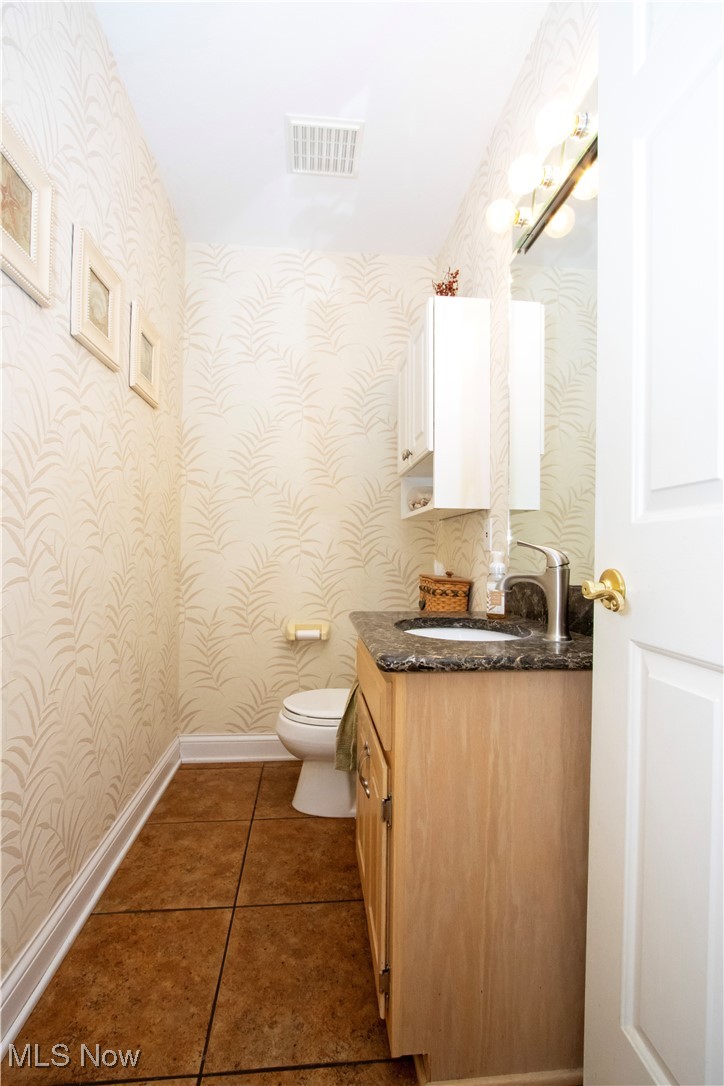 10050 Mennonite Road Rittman, OH 44270 - Photo 16 of 42 Bathroom with wallpapered walls, toilet, vanity, tile patterned flooring, and baseboards
