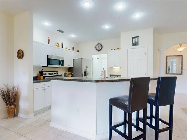 a kitchen with stainless steel appliances kitchen island granite countertop a dining table chairs and sink