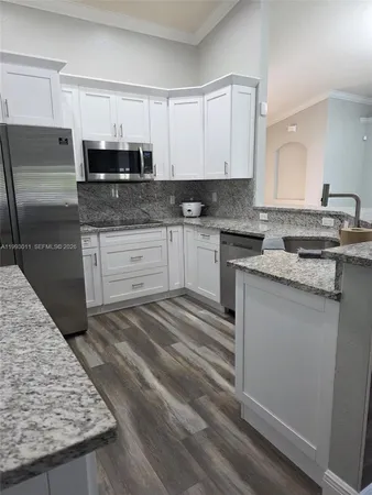 a kitchen with stainless steel appliances granite countertop a stove a sink and white cabinets