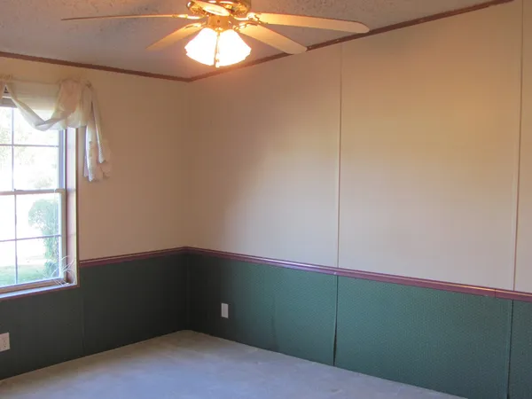 an empty room with windows and fan