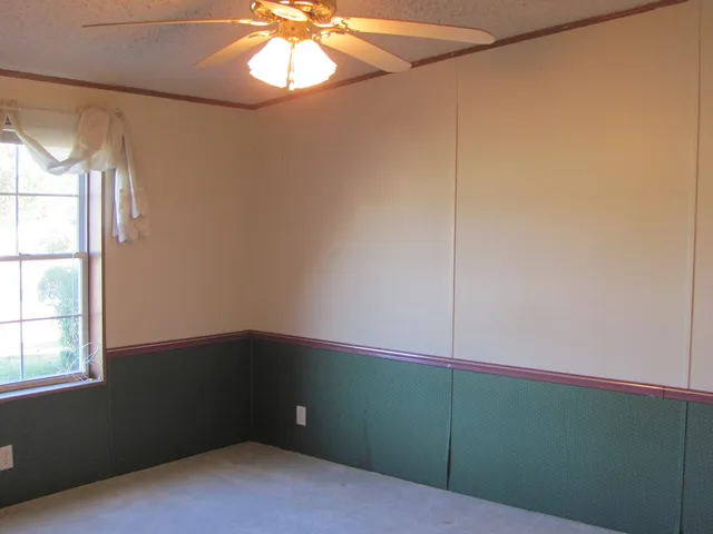 an empty room with windows and fan