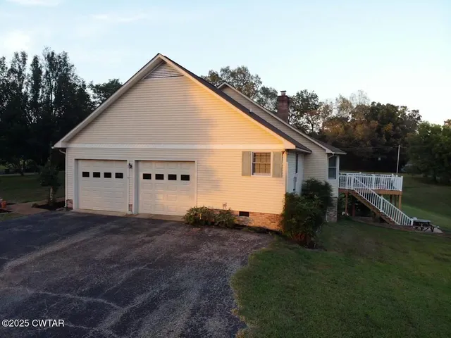 a view of a house with a yard and large tree