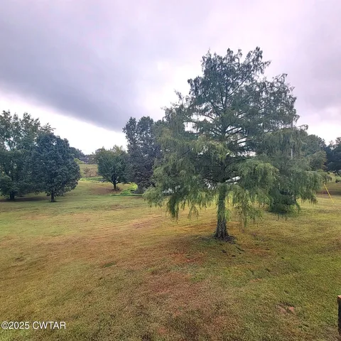 a view of a big house with a big yard and large trees