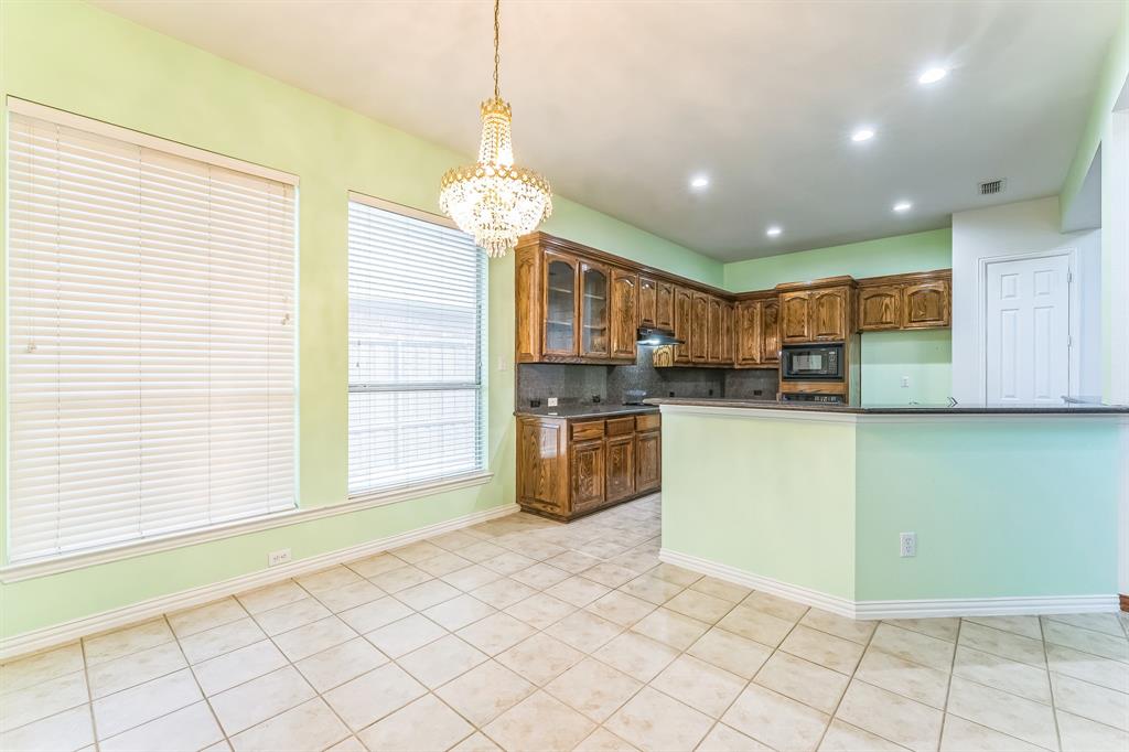 1611 Long Prairie Court Allen, TX 75002 - Photo 6 of 32 a kitchen with stainless steel appliances kitchen island granite countertop a sink a stove a microwave a counter top cabinets and a window