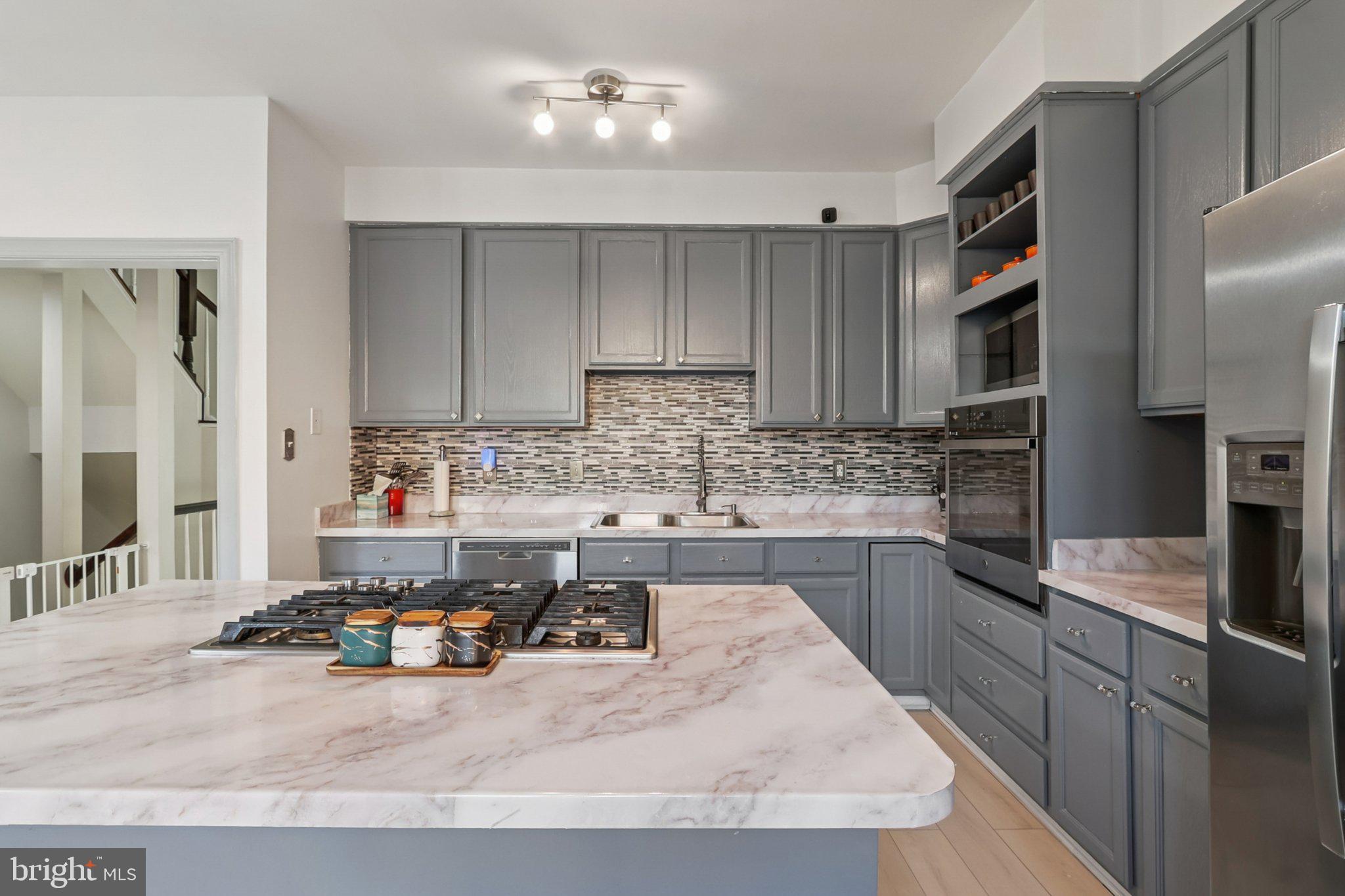 14209 Parker Farm Way Silver Spring, MD 20906 - Photo 23 of 57 a kitchen with kitchen island granite countertop a sink stove and cabinets