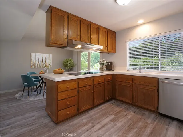 a kitchen with granite countertop wooden floors cabinets a sink and a window