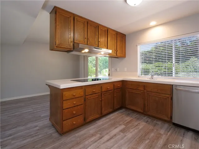 a kitchen with granite countertop wooden cabinets and a stove top oven