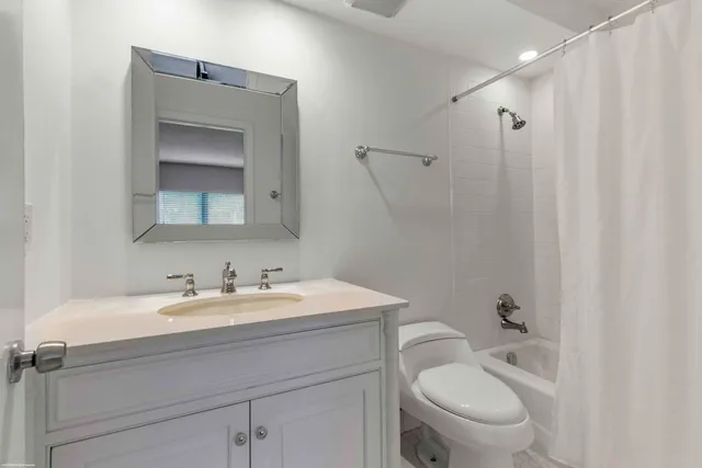 a bathroom with a toilet sink a mirror and vanity