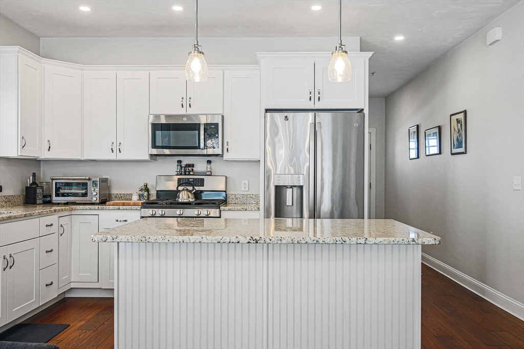 831 Ledgewood Way, Unit 831 Clinton, MA 01510 - Photo 25 of 41 a kitchen with stainless steel appliances granite countertop a refrigerator a sink dishwasher a stove and white cabinets with wooden floor
