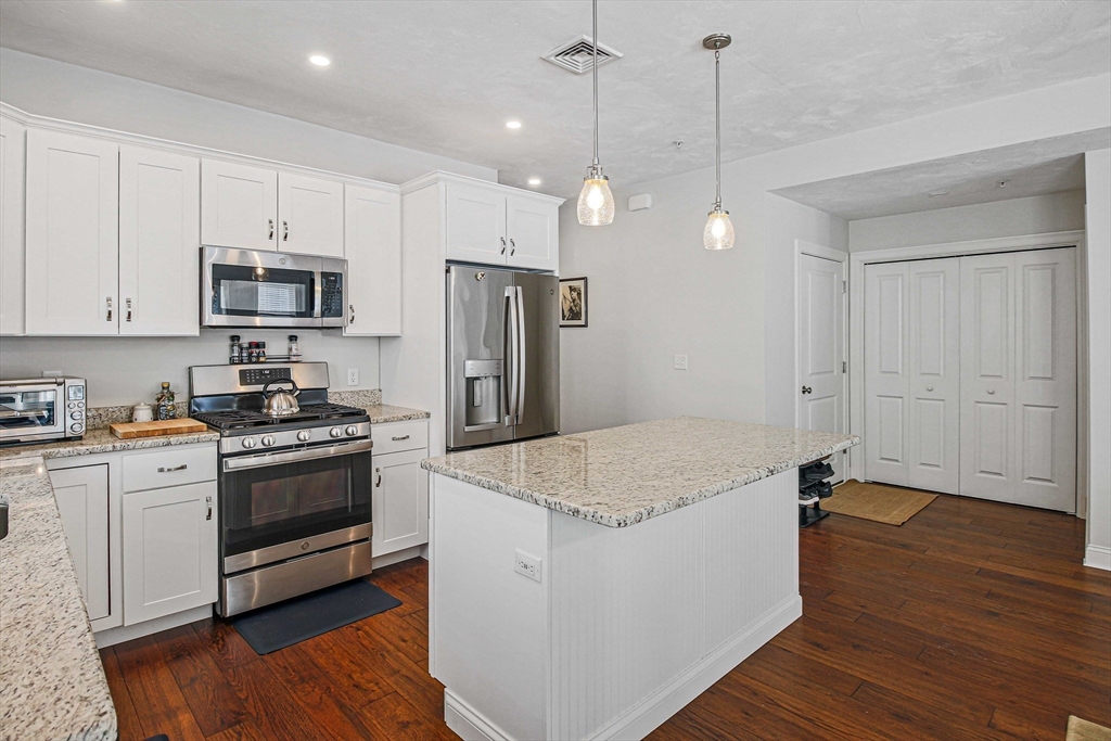 831 Ledgewood Way, Unit 831 Clinton, MA 01510 - Photo 27 of 41 a kitchen with stainless steel appliances granite countertop a sink a stove a refrigerator and island with wooden floor