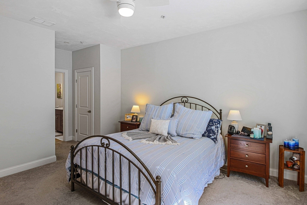 831 Ledgewood Way, Unit 831 Clinton, MA 01510 - Photo 5 of 41 a bedroom with a bed and a lamp on dresser