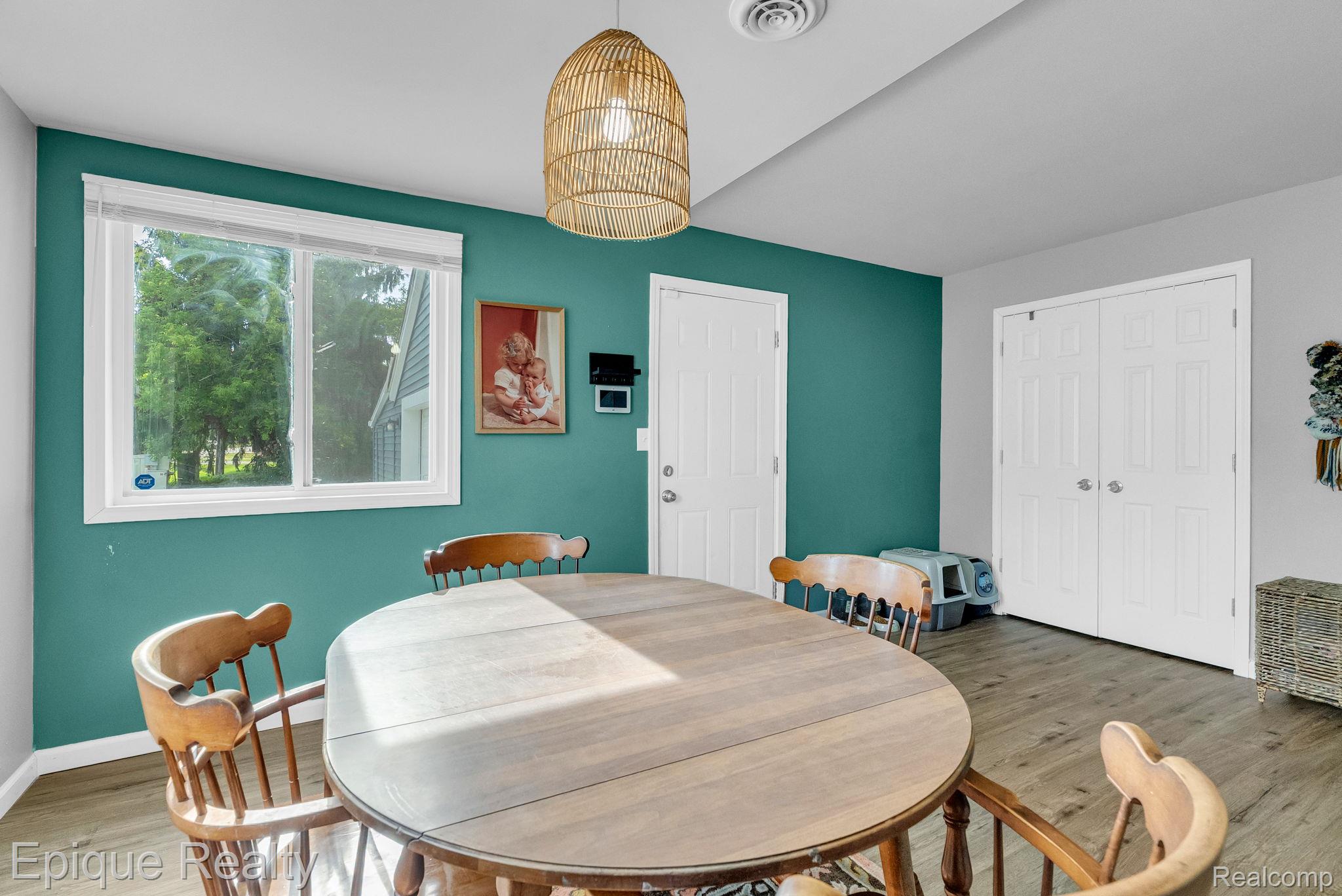 2182 North Center Road Burton, MI 48509 - Photo 17 of 34 Dining area featuring a contemporary pendant light fixture, wood-finish flooring, a white-framed window, and bi-fold doors