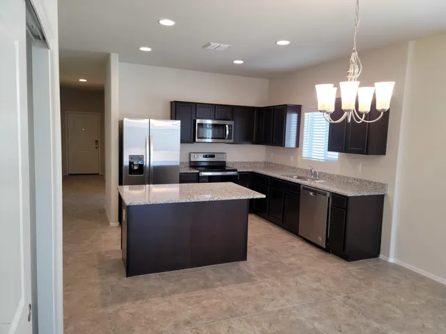 a large kitchen with stainless steel appliances a large counter top a stove a refrigerator and a sink