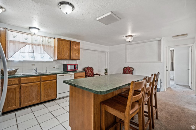 149 West 1600th Street South Mapleton, UT 84664 - Photo 10 of 44 Kitchen with wood finish cabinetry, dark countertops, tasteful backsplash, a breakfast bar area, and a textured ceiling