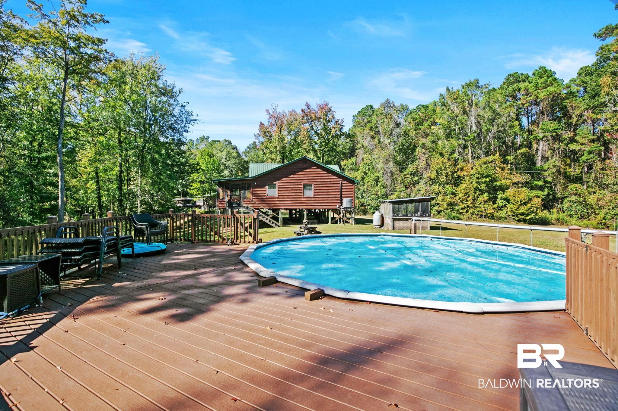 724 Rowell Lane Brewton, AL 36426 - Photo 30 of 40 View of swimming pool featuring a wooden deck, view of wooded area, and a lawn
