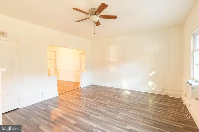 a view of empty room with wooden floor and fan