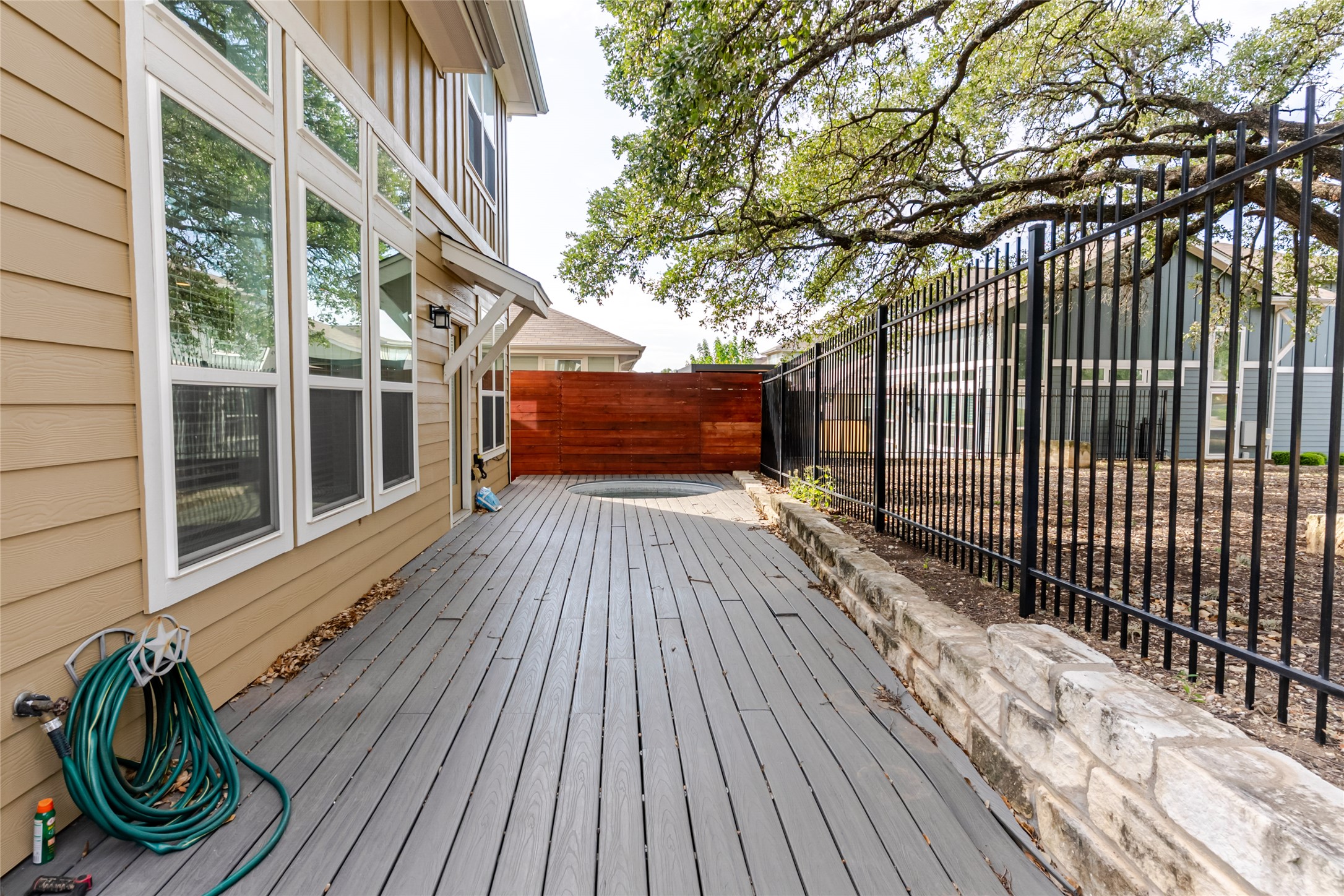 1400 Homespun Road Austin, TX 78745 - Photo 27 of 30 An inviting backyard deck features durable composite flooring flanked by professional landscaping and secure fencing.