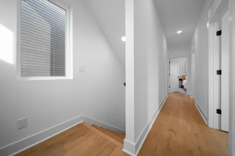 a view of a room with wooden floor and a hallway