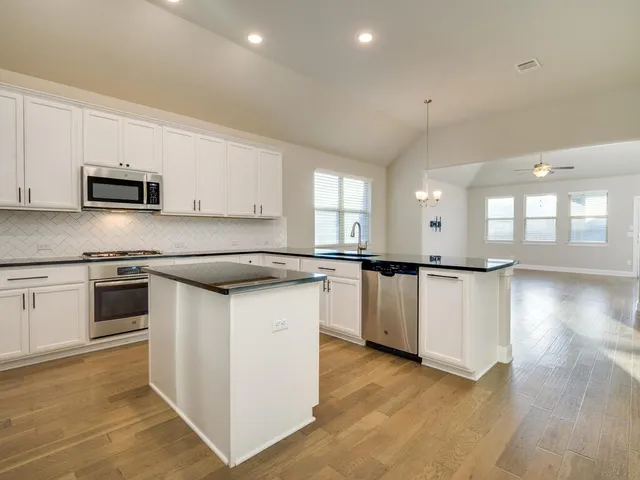 a kitchen with stainless steel appliances kitchen island granite countertop a stove a sink and a microwave