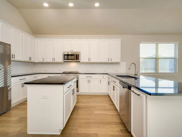 a kitchen with granite countertop a sink and a stove top oven