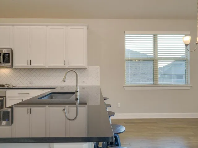 a view of kitchen with stainless steel appliances granite countertop a sink and cabinets