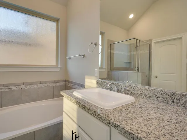 a bathroom with a granite countertop sink a mirror and a bathtub