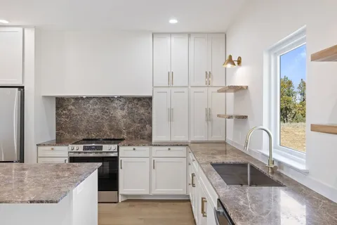 a kitchen with granite countertop white cabinets and appliances