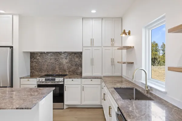 a kitchen with granite countertop white cabinets and appliances