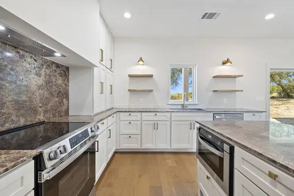 a kitchen with granite countertop a sink stainless steel appliances and cabinets