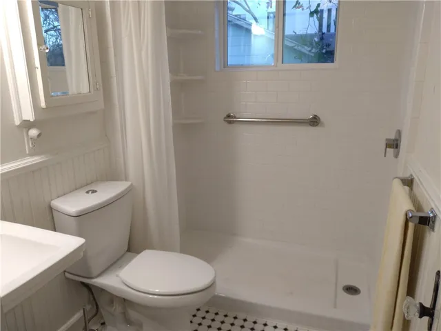 a white toilet sitting next to a shower