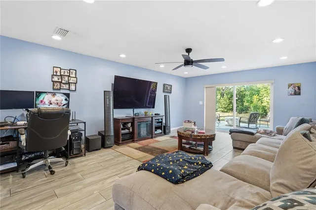 a living room with furniture a flat screen tv and a large window