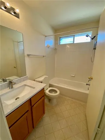 a bathroom with a granite countertop sink a toilet a mirror and shower
