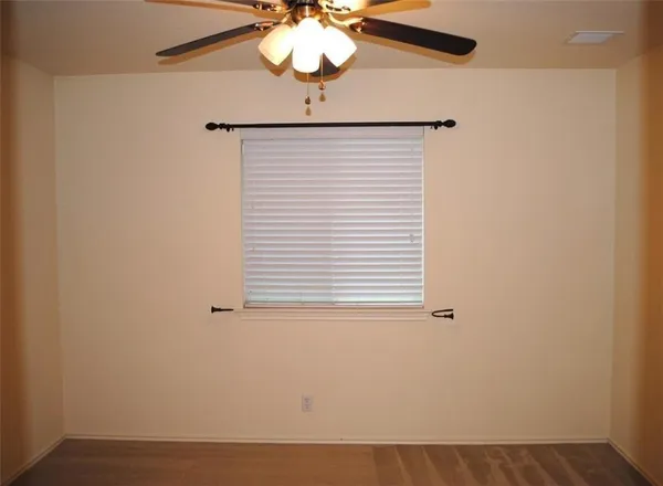 an empty room with a window and a fan