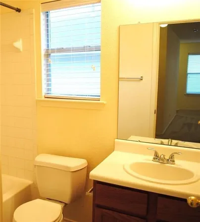 a bathroom with a granite countertop sink toilet and mirror